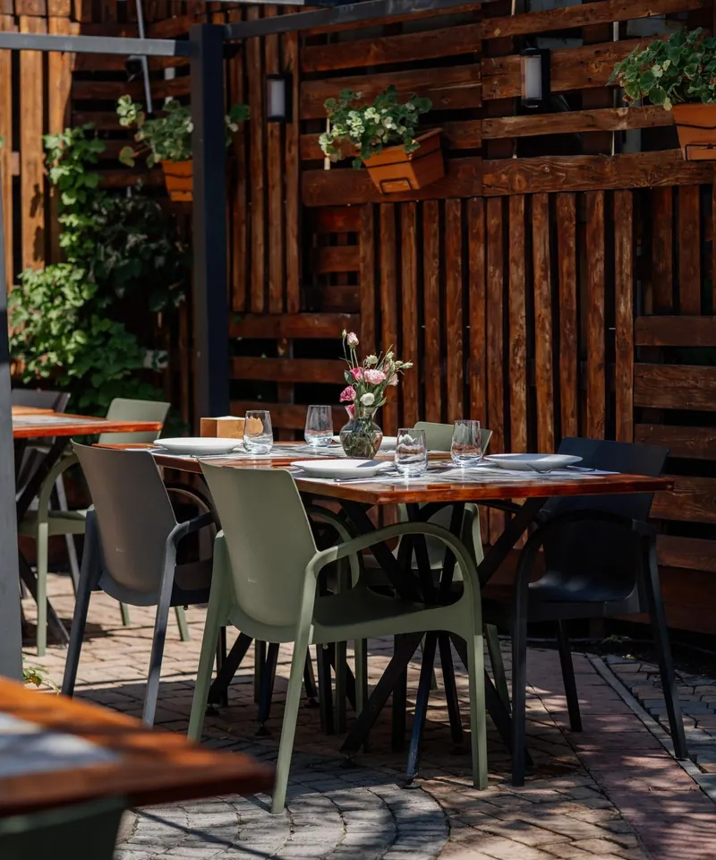 A corner of the garden with olive-green chairs and potted plants