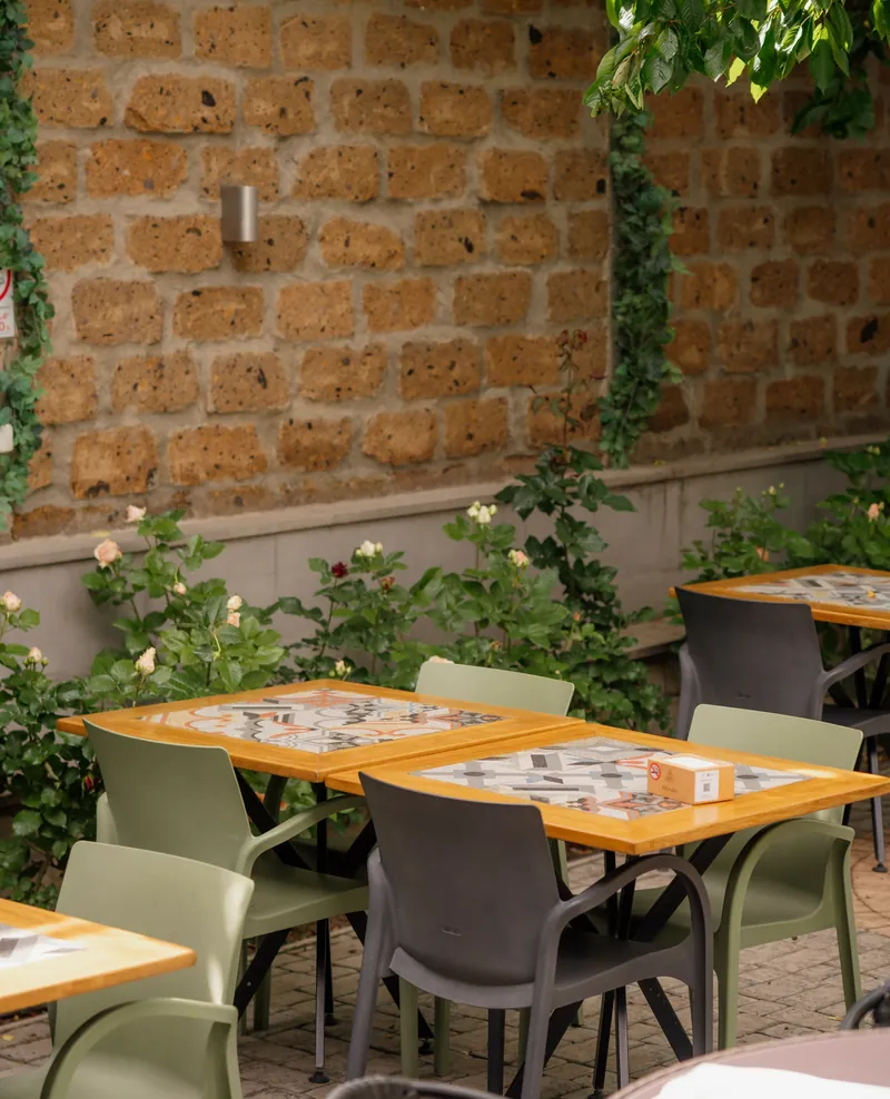 Tables in the garden by the old stone wall covered in vines