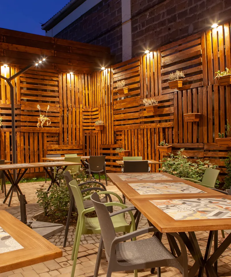 Wood-panelled garden walls with lamps and tables set for dinner