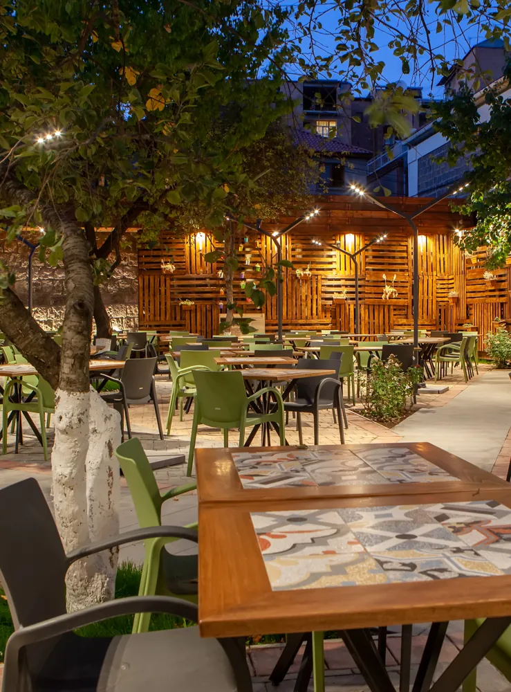 The terrace at night under the trees and string lights